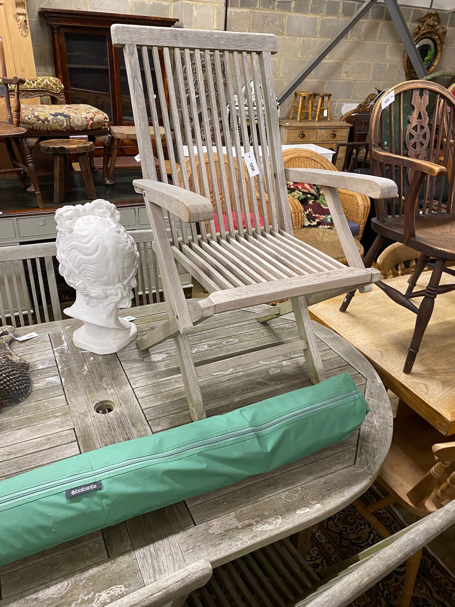 A Lindsey teak garden table with eight chairs and a parasol
